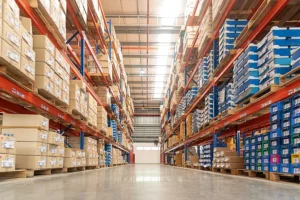 Rows of shelves with goods boxes in huge distribution warehouse in an industrial storage facility.